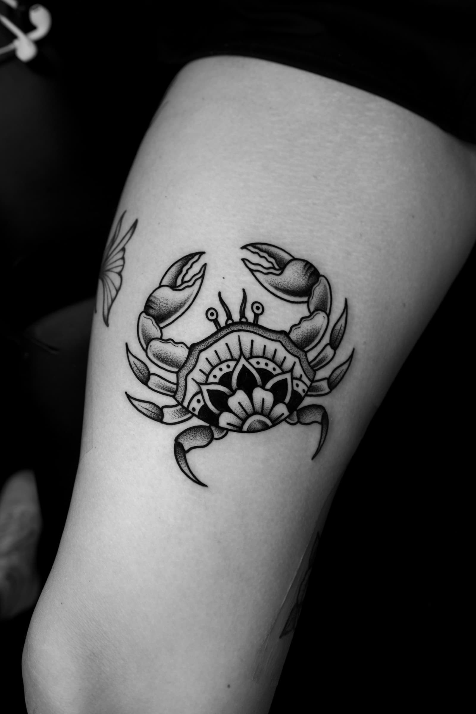 Tatouage noir et gris d’un crabe avec motif floral ornemental